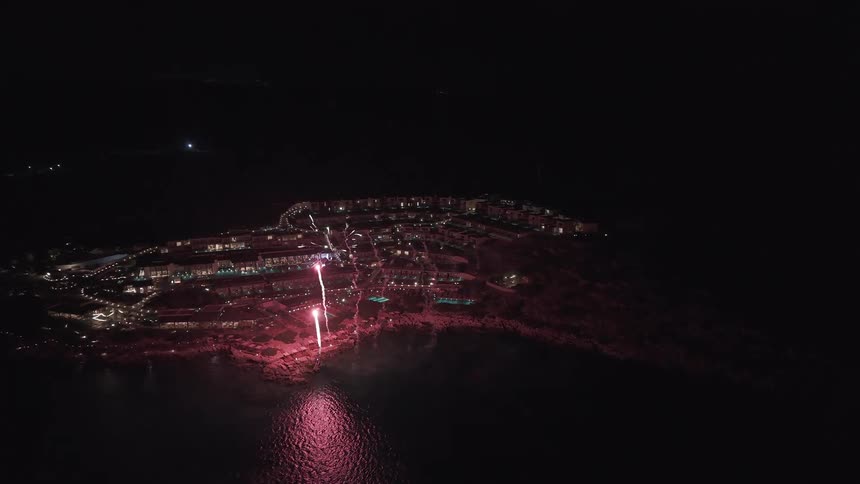 Spectacular aerial view of a vibrant fireworks display lighting up the night sky over a luxurious coastal resort