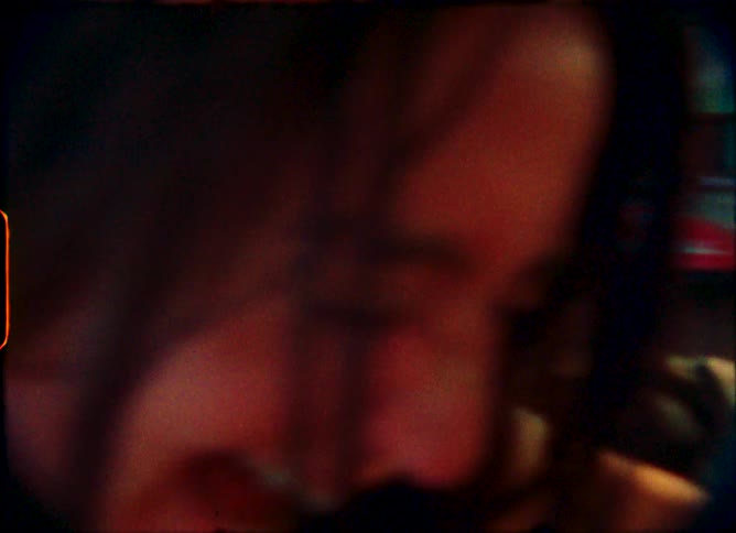 A blurry first-person view from a fast-moving amusement park ride, featuring a laughing woman, shot on vintage film