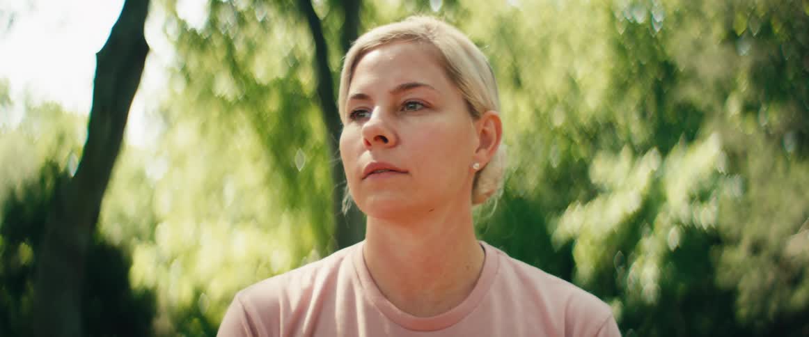Close-up of a contemplative woman enjoying a quiet, serene moment outdoors under lush green trees