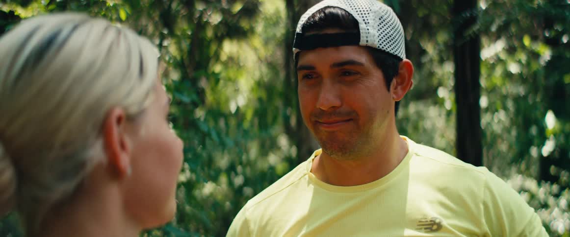 Close-up of an athletic man smiling at a woman as they take a break in a sunny forest