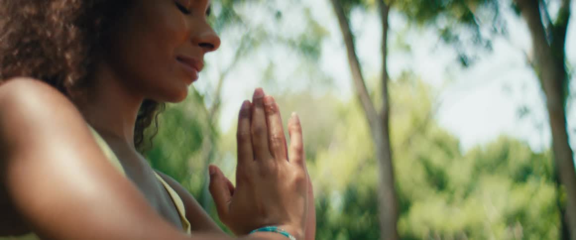Slow motion close up of a woman's hands coming together in a prayer pose for outdoor yoga and meditation