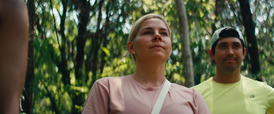 A woman sets her smartwatch before hiking with her partner in a lush green forest