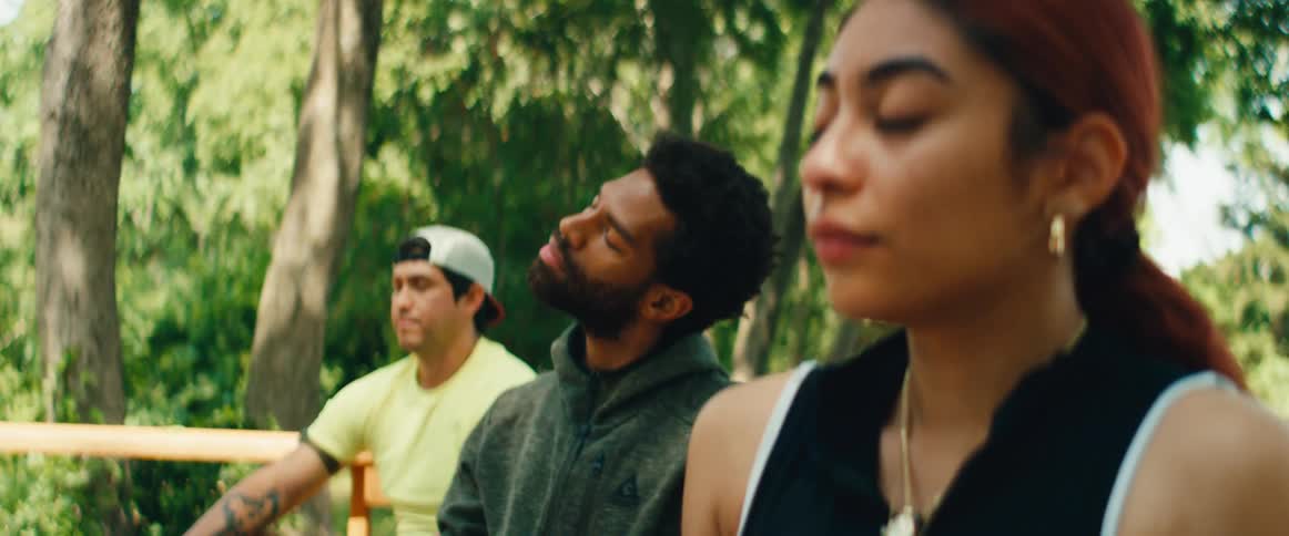 A diverse group of people find serenity and calm as they meditate together in a lush park
