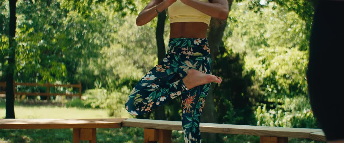 A beautiful young woman practices yoga poses in a peaceful outdoor park on a sunny day