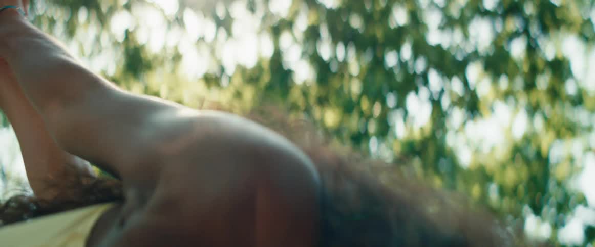 Sunlight filters through the trees as a woman and man gracefully practice yoga together in a serene park setting