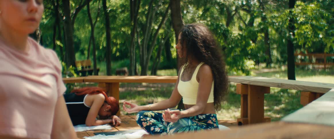 A diverse group of women stretch and meditate during a slow-motion outdoor yoga class in a tranquil park
