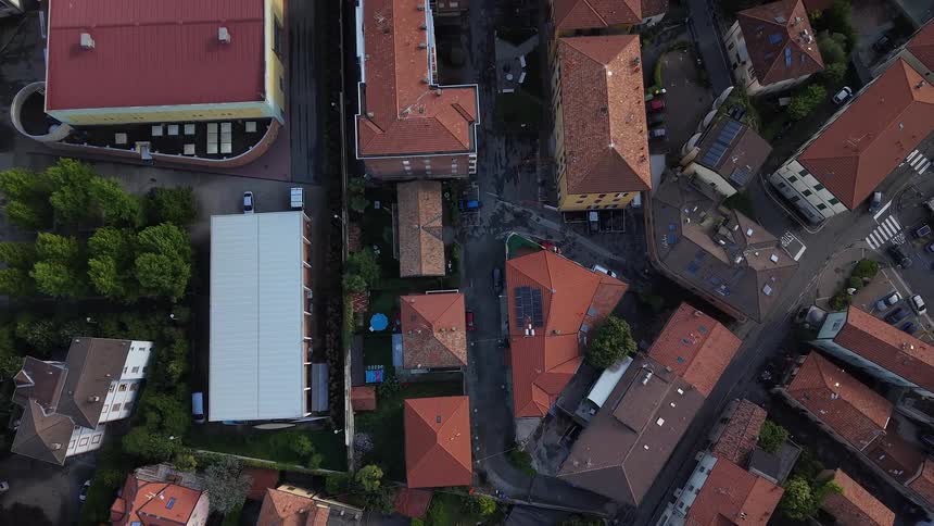 A slow aerial ascent reveals the red-tiled roofs and streets of a classic European town from a top-down perspective