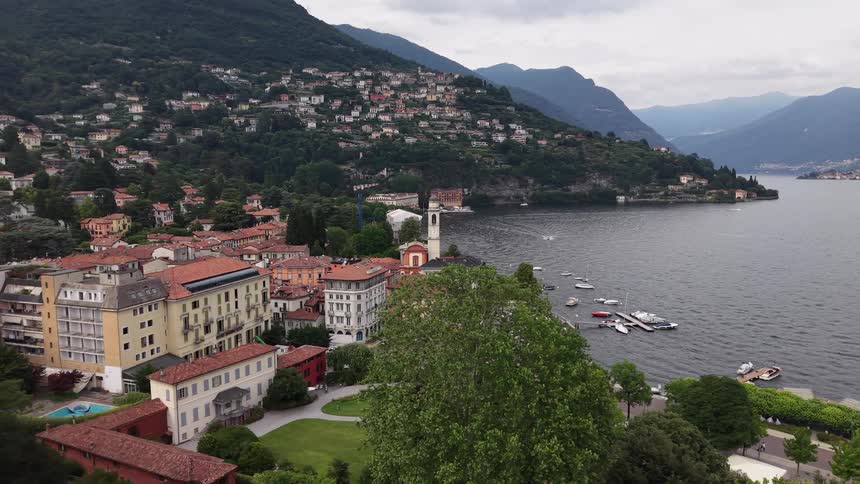 A stunning aerial view pulls back from the historic lakeside town of Cadenabbia on Lake Como, Italy, nestled among lush green mountains