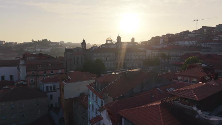 A slow aerial shot reveals the historic city of Porto, Portugal, with its iconic red rooftops bathed in the warm light of the rising sun