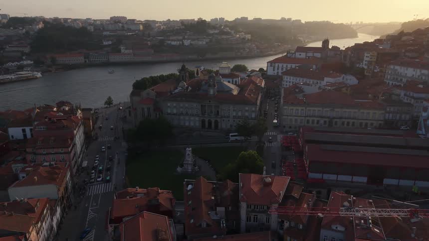 A beautiful aerial orbit reveals the historic Palácio da Bolsa in Porto, Portugal, during a glowing sunrise over the Douro River
