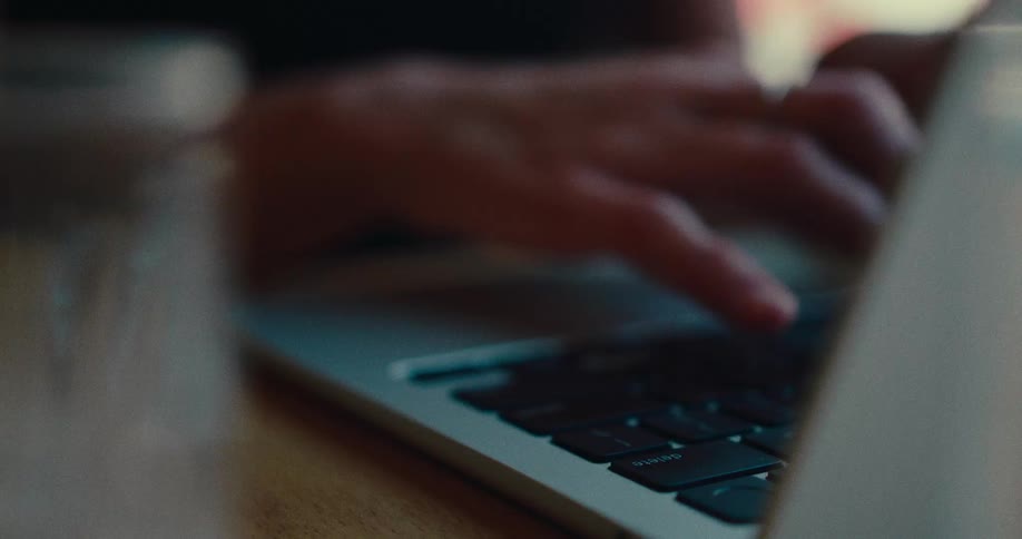 Close-up cinematic shot of a person's hand typing on a laptop keyboard