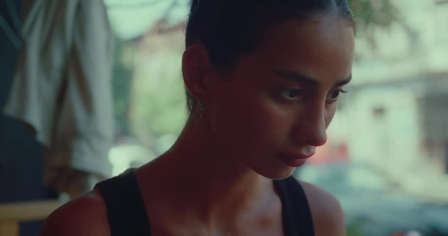 An introspective young woman is lost in thought while sitting in a quiet, naturally lit room
