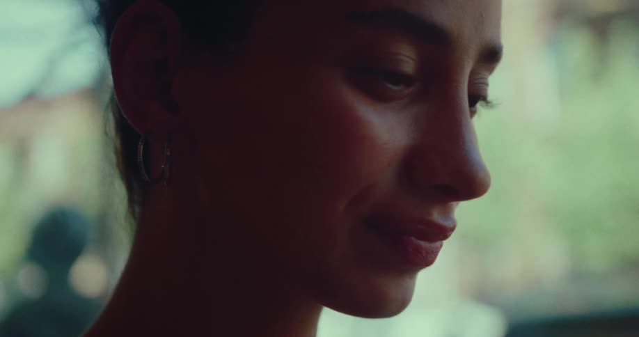 Close-up profile of a beautiful young woman smiling softly in a moment of quiet contemplation