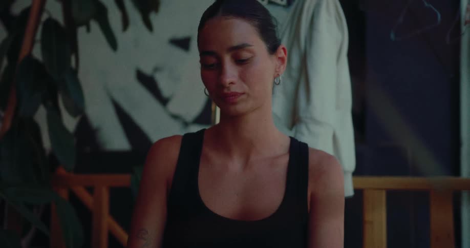 A thoughtful woman with tattoos closes her laptop in a cozy, dimly lit cafe and takes a moment to herself
