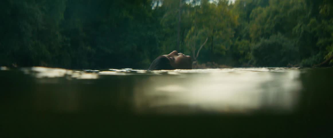 A young boy and an elephant peacefully swim and float in a tranquil jungle river