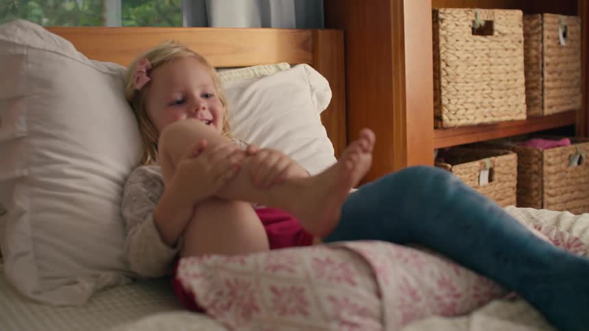 Smiling young girl relaxes on a bed with a blue leg cast in a cozy bedroom
