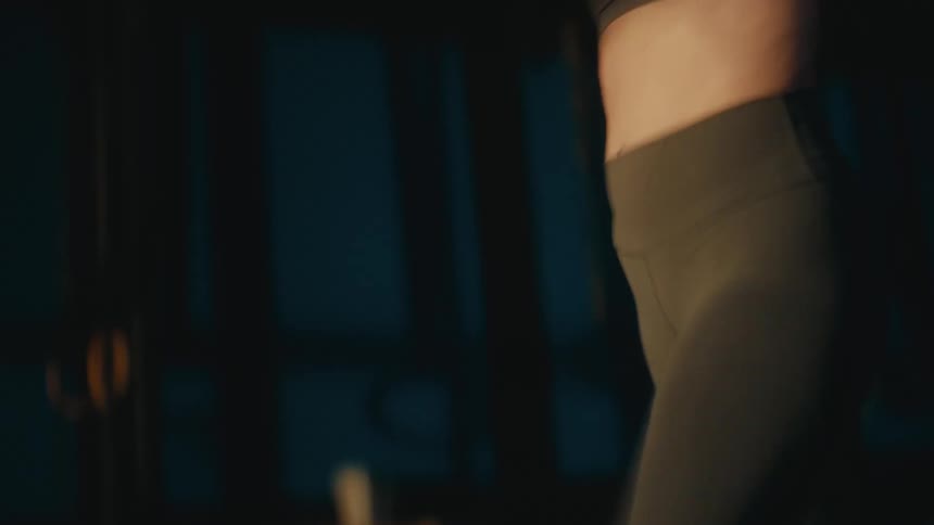 Close-up of a fit woman's legs running in place during an intense cardio workout in a dark gym