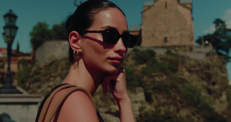 A close-up of a stylish woman in sunglasses thoughtfully admiring a historic landmark on a sunny day