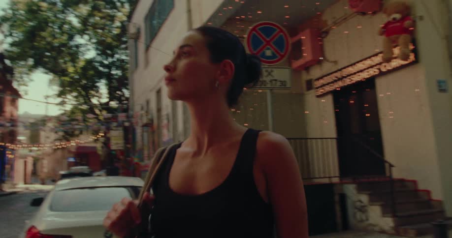 A stylish woman confidently walks down a charming, narrow cobblestone street in an old city