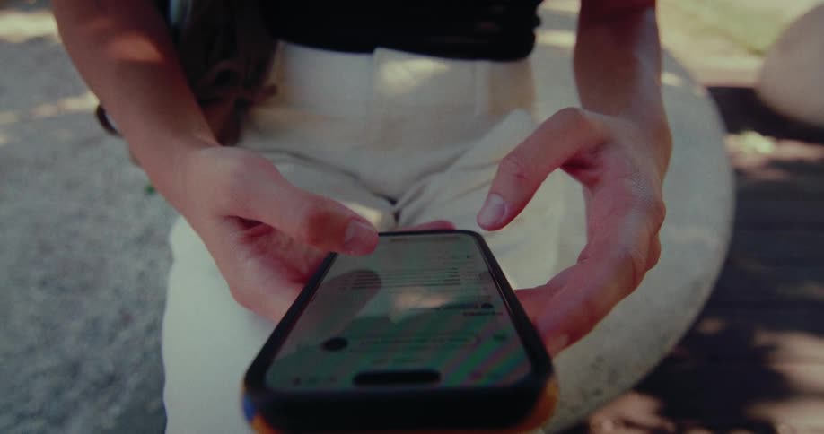 Front view close-up of a woman's hands using a smartphone to scroll through her social media feed