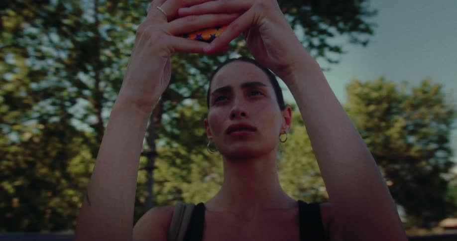 A young woman with tattoos captures memories of a historic European city on her smartphone on a sunny day