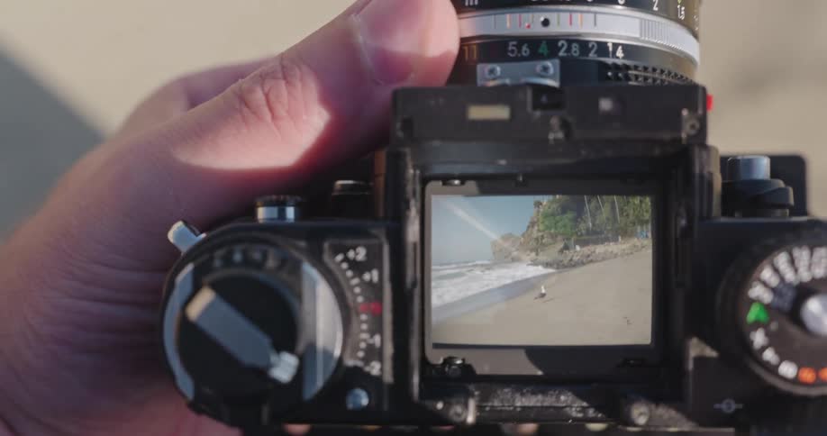 A photographer's point of view while framing a sunny beach scene with a vintage film camera