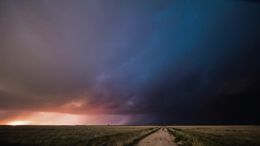 A view of a field with storm clouds moving above