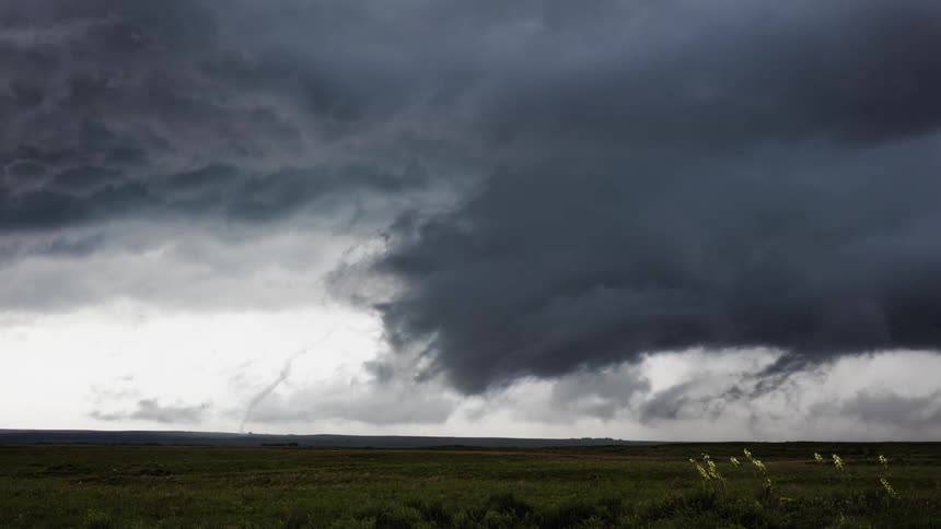 Clouds swirl and form above a flat prairie