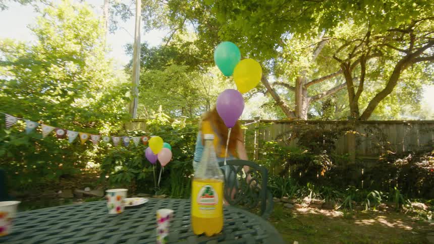 A group of happy kids have a messy food fight with whipped cream at a sunny backyard birthday party