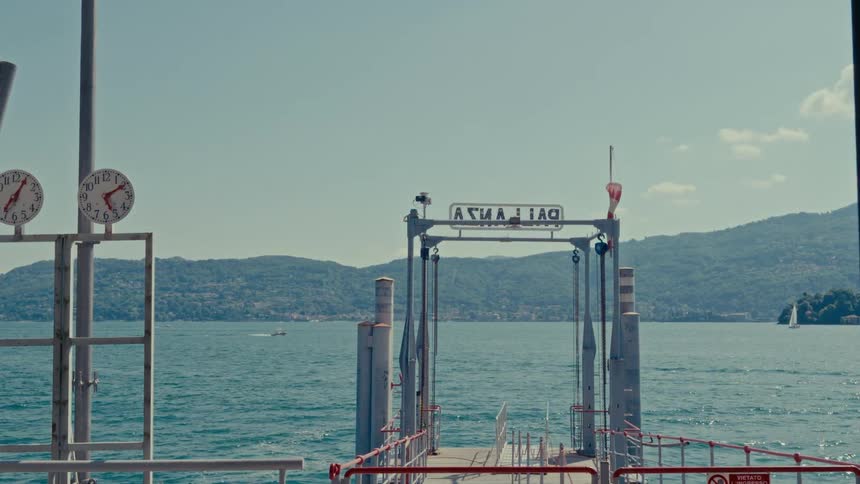 A tranquil view from the Pallanza ferry dock overlooking the calm waters of Lake Maggiore on a sunny day
