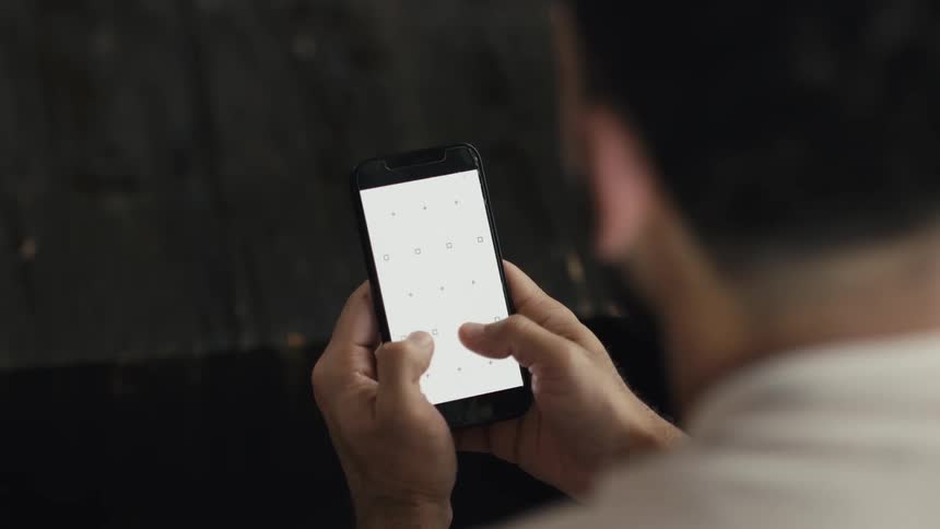 Over-the-shoulder close-up of a man scrolling on a smartphone with a blank screen prepared for screen replacement