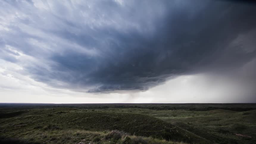 Dark clouds swirl and move across a plain