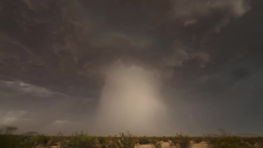 A powerful thunderstorm unleashes a microburst and frequent lightning strikes over the vast desert landscape