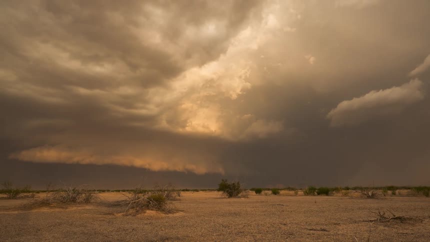 A dramatic time-lapse captures a massive haboob turning a fiery orange as it rolls across the desolate desert landscape