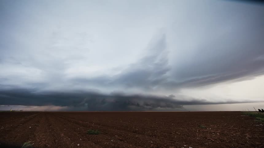 Storm clouds form over an open field while lightning flashes
