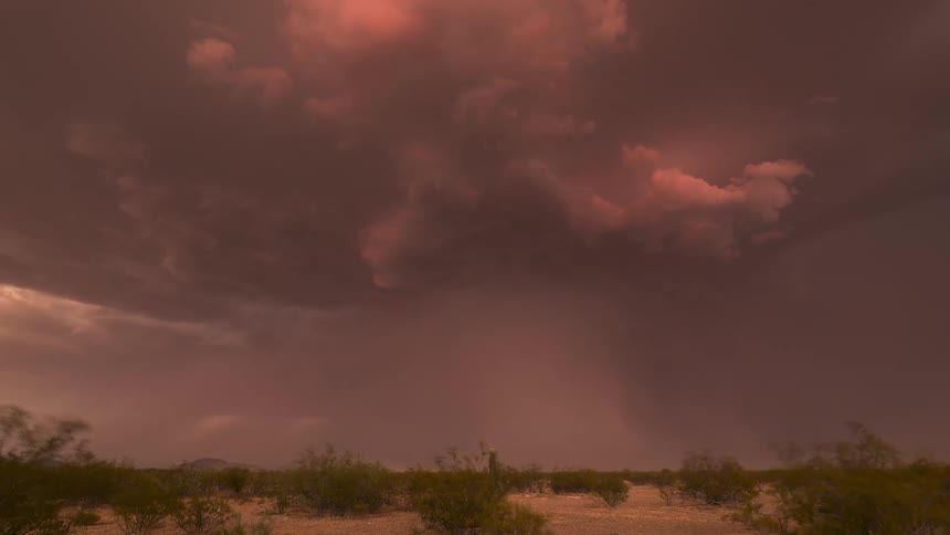 A powerful thunderstorm unleashes dramatic lightning strikes under surreal red clouds in a desert time-lapse