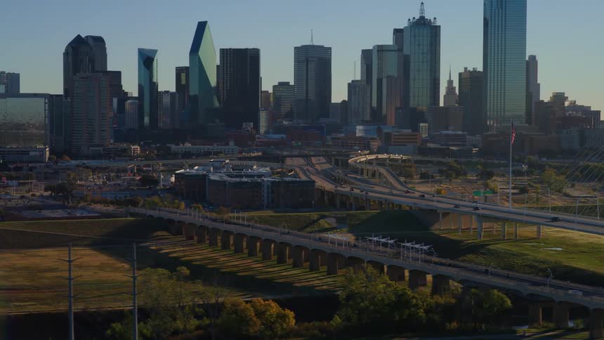 A slow aerial pullback reveals the stunning Dallas, Texas skyline and the iconic Margaret Hunt Hill Bridge during a beautiful golden hour