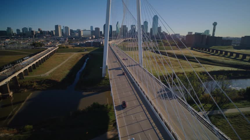 A beautiful aerial shot flies over the Margaret Hunt Hill Bridge toward the Dallas skyline on a sunny morning