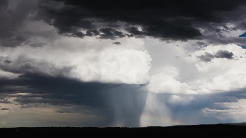 Storm clouds form and drop rain across a plain