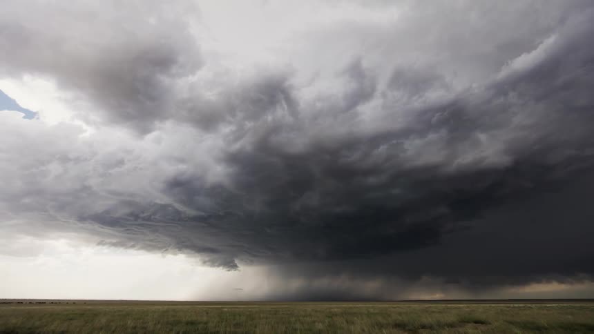 Clouds moving quickly to form a tornado in an open field