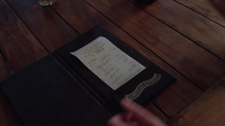 A woman reviews the restaurant bill and takes out her wallet to pay for the meal