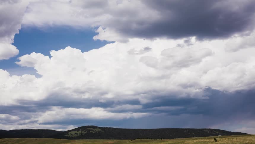 White clouds in a blue sky move over a field
