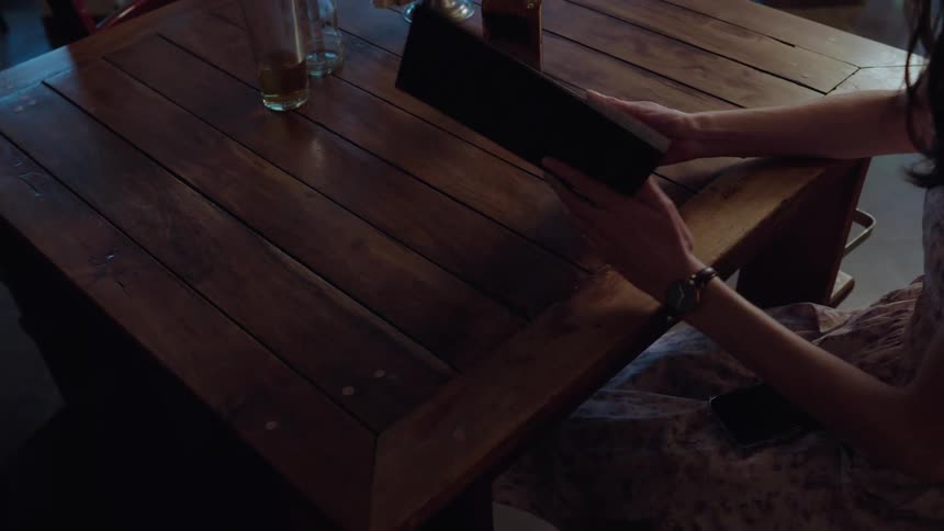 Close up of a woman's hands receiving a menu and opening it at a restaurant table