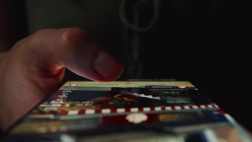 Close-up of a person's thumb endlessly scrolling through a social media feed on a phone in a dark room