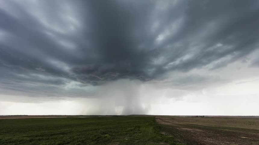 Clouds forming and flowing across sky while rain falls on field