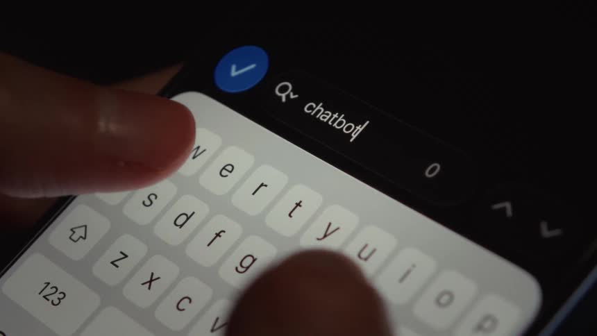 A close-up view of fingers typing the word 'chatbot' into a smartphone's search bar