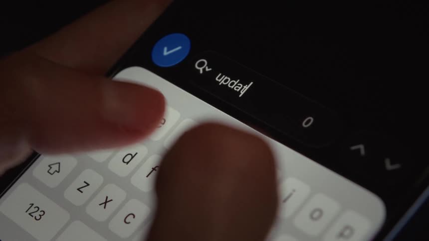 A close-up of a person's finger typing the word 'update' into a search bar on a smartphone screen