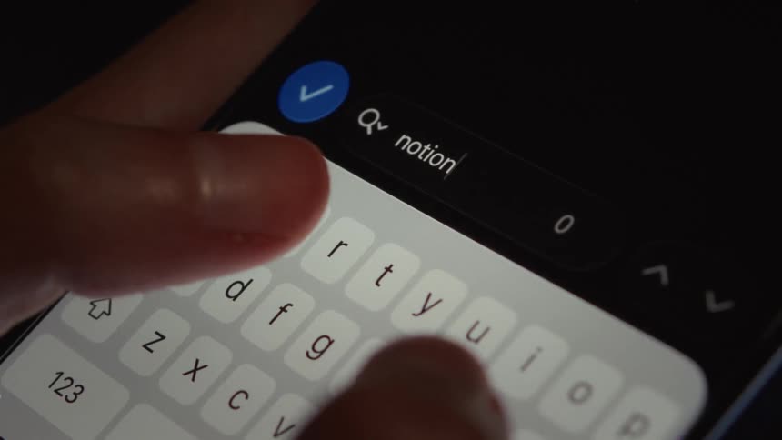 A close-up of a person's fingers typing the word 'notion' into a smartphone search bar