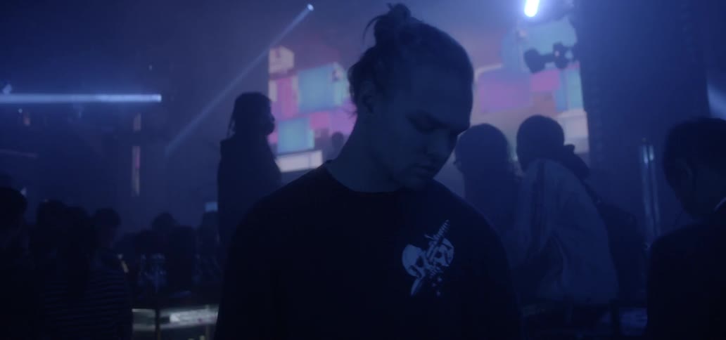 A young man mills about inside a club