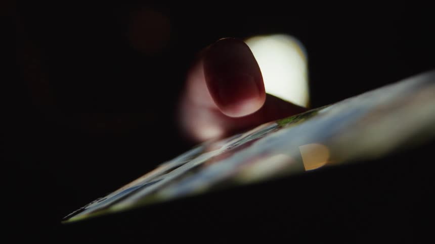 Extreme close-up of a finger navigating a touchscreen on a digital tablet in the dark